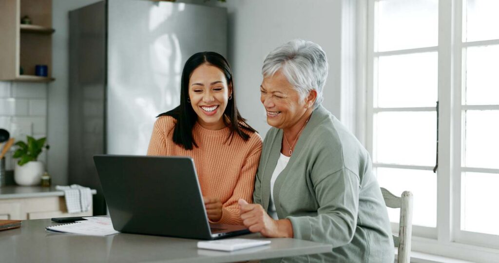 A mother and daughter reviewing finances on a laptop at home